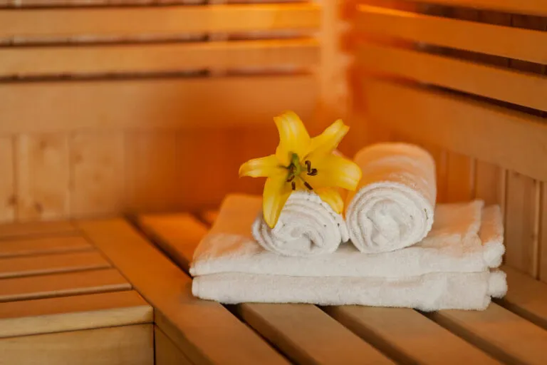 Serviettes dans un sauna avec une fleur jaune posée dessus